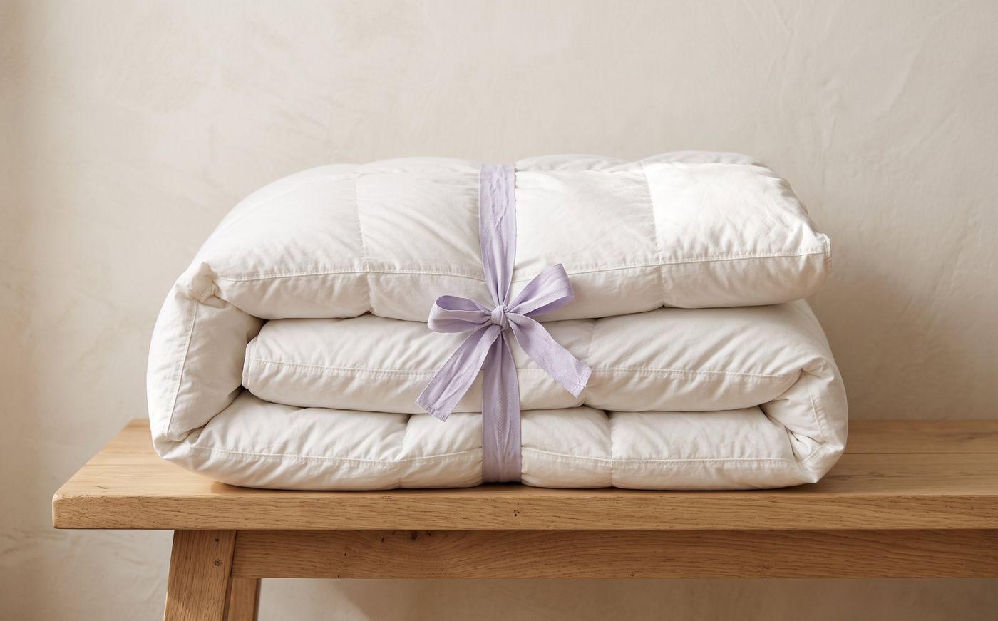 A folded white duvet tied with a lavender ribbon
